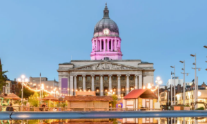 Illuminated domed building in city square with fountains at night