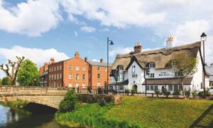 Stone bridge beside thatched-roof pub in quaint English village