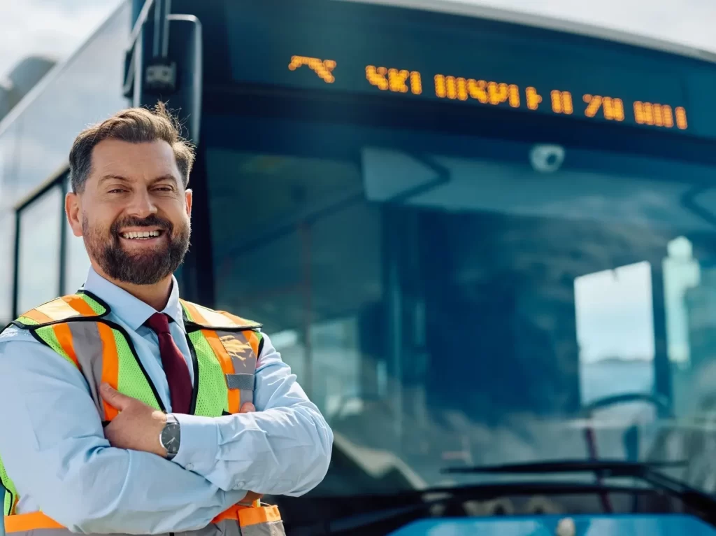 Bus worker in safety vest standing near bus