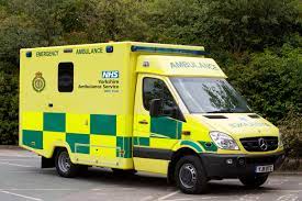 Yellow-green NHS ambulance parked near trees